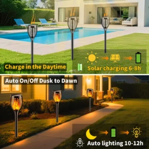 Decorative solar torch lights with flickering flame effect illuminating a garden pathway at dusk.